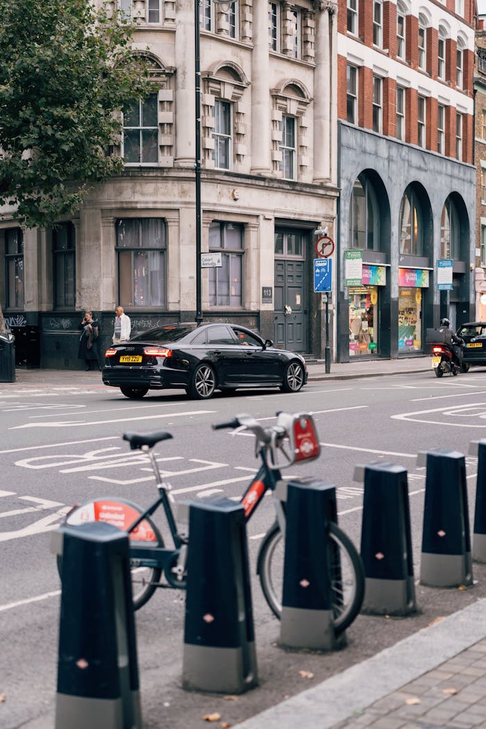 Urban street scene showing bicycles parked and cars driving by a historic building.